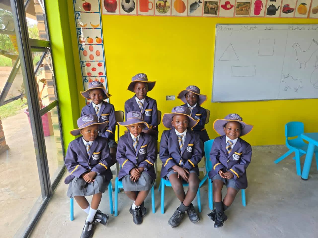 A classroom group photo showing multiple students posing at their desks.