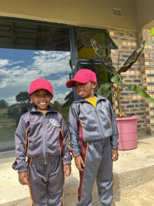 Two smiling boys in grey and gold sports tracksuits teasing each other.