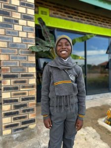 A senior primary boy posing proudly in his full MGK Academy grey and gold school uniform.