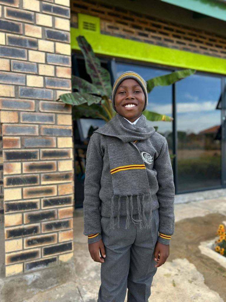 A senior primary boy posing proudly in his full MGK Academy grey and gold school uniform.