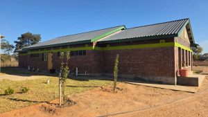 The distinct blocks of the new MGK Academy school campus under a bright blue sky.